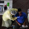 Nhân viên y tế lấy mẫu dịch xét nghiệm COVID-19 cho người lao động tại Singapore. (Ảnh: AFP/TTXVN)