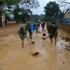 Bộ đội giúp địa phương xã Hướng Việt thu dọn bùn đất trên các tuyến giao thông. (Ảnh: Hồ Cầu/TTXVN)