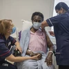 Nhân viên y tế tiêm vắcxin phòng COVID-19 của Pfizer-BioNTech cho người dân tại London, Anh, ngày 8/12. (Ảnh: AFP/TTXVN)