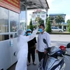 Cán bộ nhân viên y tế của Bệnh viện Đa khoa tỉnh Lai Châu kiểm soát đo thân nhiệt cho người dân trước khi vào khám bệnh. (Ảnh: Quý Trung/TTXVN)