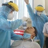 Các y bác sỹ Trung tâm y tế quận 7 thực hiện xét nghiệm sàng lọc COVID-19 ngẫu nhiên cho công nhân tại Công ty TNHH Kim may Organ Việt Nam. (Ảnh: Thanh Vũ/TTXVN)