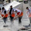Các tình nguyện viên dọn dẹp đống đổ nát của các tòa nhà bị sập sau loạt không kích của Israel xuống Dải Gaza, ngày 23/5. (Ảnh: THX/TTXVN)