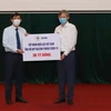 Tổng Giám đốc EVN Trần Đình Nhân trao tượng trưng tiền ủng hộ Quỹ Vaccine phòng COVID-19 cho Bộ trưởng Bộ Y tế Nguyễn Thanh Long. (Ảnh: TTXVN phát)