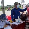 Đoàn viên thanh niên tham gia đo thân nhiệt tại chốt kiểm dịch ở cầu Mỹ Lợi, thị xã Gò Công, Tiền Giang. (Ảnh: Hữu Chí/TTXVN)