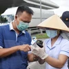 Nhân viên y tế hướng dẫn người đi từ Thành phố Hồ Chí Minh về Đồng Nai thực hiện khai báo y tế tại chốt kiểm soát trên Quốc lộ 51, đoạn giao với cao tốc Thành phố Hồ Chí Minh-Long Thành-Dầu Giây. (Ảnh: Lê Xuân/TTXVN)