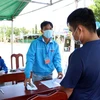 Lực lượng trực chốt kiểm soát dịch bệnh huyện Ninh Hải kiểm tra giấy xác nhận và đo thân nhiệt người dân đi, về địa phương. (Ảnh: Công Thử/TTXVN)