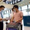 Nhân viên của Vietnam Airlines kiểm tra giấy tờ của hành khách trước khi vào làm thủ tục. (Ảnh: Huy Hùng/TTXVN)