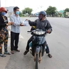 Tặng các suất cơm, nước uống miễn phí cho những người trở về quê bằng xe máy từ các tỉnh, thành phía Nam trên Quốc lộ 1A đoạn qua thành phố Phan Rang-Tháp Chàm, tỉnh Ninh Thuận. (Ảnh: Nguyễn Thành/TTXVN)