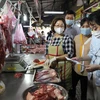 Cán bộ Ban quản lý kiểm tra chứng từ chứng minh nguồn gốc thực phẩm của tiểu thương tại chợ Phạm Văn Hai, Thành phố Hồ Chí Minh. (Ảnh: Hồng Giang /TTXVN)