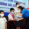 Lãnh đạo Đoàn thanh niên Thành phố Hồ Chí Minh cùng các mạnh thường quân tặng học bổng cho các em học sinh mồ côi do dịch COVID-19. (Ảnh: Thanh Vũ/TTXVN)