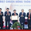 Chủ tịch nước Nguyễn Xuân Phúc trao Bằng chứng nhận huyện đạt chuẩn nông thôn mới cho lãnh đạo huyện Tuy Phước. (Ảnh: Thống Nhất/TTXVN)