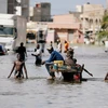 Người dân đi qua một con phố ngập lụt sau trận mưa lớn ở Senegal. (Nguồn: chinadaily.com)