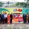 Các đại biểu chụp hình lưu niệm bên bức tranh vẽ cổ động về tình hữu nghị nhân dân Việt Nam-Cuba. (Ảnh: Tiến Lực/TTXVN)