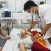 Bệnh nhi mắc bệnh tay chân miệng được bác sĩ Bệnh viện Phụ sản- Nhi Đà Nẵng khám. (Ảnh: Văn Dũng/TTXVN)