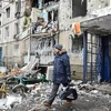 Người dân rời khỏi một tòa nhà đổ nát sau vụ pháo kích tại thành phố Kharkiv, Ukraine, ngày 8/3/2022. (Ảnh: AFP/TTXVN)