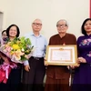 Phó Bí thư Thường trực Thành ủy Hà Nội Nguyễn Thị Tuyến trao tặng huy hiệu 85 năm tuổi Đảng cho lão thành cách mạng Mai Vy. (Ảnh: TTXVN phát)
