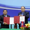Chủ tịch Ủy ban Nhân dân tỉnh An Giang Nguyễn Thanh Bình (phải ) và ngài Ouch Phea, Tỉnh trưởng tỉnh Takeo (Vương quốc Campuchia) ký thỏa thuận hợp tác giữa hai tỉnh trong thời gian tới. (Ảnh: Công Mạo/TTXVN)