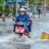 Nước ngập sâu trên tuyến đường ven hồ Búng Xáng khiến việc đi lại của người dân gặp khó khăn. (Ảnh: Thanh Liêm/TTXVN)