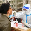 Nhân viên y tế lấy mẫu xét nghiệm COVID-19 cho người dân tại tỉnh Cam Túc, Trung Quốc. (Ảnh: AFP/TTXVN)