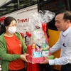 Lãnh đạo Saigon Co.op tặng quà cho người lao động trước khi khởi hành “Chuyến xe hạnh phúc” đưa người lao động về quê ăn Tết. (Ảnh: Thanh Vũ/TTXVN)