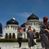 Khách du lịch nước ngoài thăm nhà thờ Hồi giáo Baiturrahman ở Banda Aceh của Indonesia. (Ảnh: AFP/TTXVN)