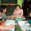 Cô giáo Ngọc Tâm thủy tinh hướng dẫn học sinh làm bài tập tại lớp học “5 không.” (Ảnh: Văn Đạt/TTXVN)