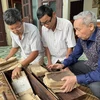 Các thành viên ban quản lý di tích Đền Quốc Tế ở xã Dị Nậu, huyện Tam Nông, tỉnh Phú Thọ, bên các cuốn sách cổ và sắc phong hiện đang được lưu giữ tại nhà dân. (Ảnh: Đào An/TTXVN)