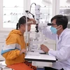 Thạc sỹ-bác sỹ chuyên khoa mắt Nguyễn Hữu Thế, thăm khám cho bệnh nhi đau mắt đỏ. (Ảnh: Minh Phú/TTXVN)