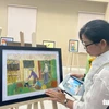 Chị Đoàn Nguyên Thùy xúc động khi nhìn lại những bức tranh do chồng mình, anh Phạm Minh Đức vẽ bằng tay trái khi còn sống. (Nguồn: Báo Tuổi trẻ)