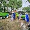Các giáo viên khẩn trương dọn dẹp bùn non trên sân trường. (Ảnh: Mai Trang/TTXVN)