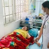 Bác sỹ của một trung tâm Y tế huyện thăm khám cho các bệnh nhân bị ngộ độc sau khi đi ăn đám cưới. (Ảnh: TTXVN phát)