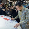 Đại sứ Việt Nam tại Indonesia Tạ Văn Thông ký tên vào chiếc xe trưng bày của Vinfast. (Ảnh: Đỗ Quyên/Vietnam+)