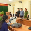 Lực lượng chức năng đọc lệnh bắt 2 đối tượng Nguyễn Tứ và Đinh Đức Minh. (Ảnh: TTXVN phát)