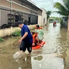 Cán bộ, chiến sỹ Ban Chỉ huy Quân sự thành phố Phú Quốc, tỉnh Kiên Giang, cùng với lực lượng địa phương ứng cứu, sơ tán người dân đến nơi an toàn do mưa lớn gây ngập cục bộ trên đảo. (Ảnh: TTXVN phát)