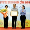 Phó Chủ tịch UBND Thành phố Hồ Chí Minh Trần Thị Diệu Thúy trao quyết định công nhận quận Phú Nhuận hoàn thành mục tiêu không còn hộ nghèo đa chiều thành phố giai đoạn 2021-2025. (Ảnh: Thanh Vũ/TTXVN)