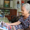Bà Chín Xinh xem lại hình ảnh hoạt động của Hội cựu kháng chiến. (Ảnh: Thanh Bình/TTXVN)