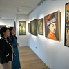 Nhân viên phòng tranh Thăng Long Art Gallery giới thiệu về các tác phẩm với khách tham quan. (Ảnh: TTXVN phát)