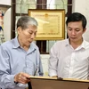 Ông Nguyễn Hữu Luyên cùng con trai ôn lại truyền thống vẻ vang của các liệt sỹ, Bà mẹ Việt Nam anh hùng trong gia đình. (Ảnh: PV/Vietnam+)