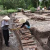 Các nhà khảo cổ đo diện tích nền gạch cổ tại một điểm khai quật tại khu di tích Gò Tháp. (Ảnh: TTXVN)