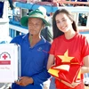 Hoa hậu Tiểu Vi trao cờ và tủ thuốc cho 1 chủ tàu. (Ảnh: Tùng Lâm/Vietnam+)