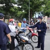 Lực lượng chức năng kiểm tra phiếu tại cổng chợ (Ảnh: Hoàng Đạt/Vietnam+)