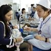 Nhân viên y tế làm thủ tục tiêm chủng cho trẻ tại Trung tâm Y tế Dự phòng Hà Nội. (Ảnh: Dương Ngọc/TTXVN)