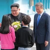 Tổng thống Hàn Quốc Moon Jae-in và Nhà lãnh đạo Triều Tiên Kim Jong-un nhận hoa chúc mừng từ các em thiếu nhi Hàn Quốc tại lễ đón ở quảng trường làng đình chiến Panmunjom ngày 27/4. (Nguồn: YONHAP/TTXVN)