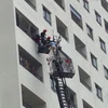 Cảnh sát chữa cháy phải dùng búa, rìu để phá cửa giải cứu những người bị mắc kẹt trong tòa nhà. (Ảnh: PV/Vietnam+)