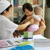 Nhân viên y tế khám sàng lọc sức khỏe cho trẻ trước khi tiêm. (Ảnh: Dương Ngọc/TTXVN)