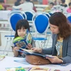 Học sinh và phụ huynh tranh thủ đọc sách, báo trong khi chờ thi tại trường Tiểu học Công nghệ Giáo dục Hà Nội. (Ảnh: CTV/Vietnam+)