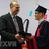 Hiệu trưởng trường Đại học Việt-Đức Jürgen Mallon trao bằng tốt nghiệp cho sinh viên. (Ảnh: Dương Chí Tưởng/TTXVN)