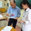 Giám thị kiểm tra thông tin của thí sinh trước khi vào phòng thi Trung học phổ thông quốc gia. (Ảnh: PM/Vietnam+)