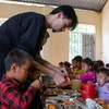 Ca sỹ Đen Vâu cẩn thận bóc tôm cho học sinh vùng cao trong bữa ăn bán trú. (Ảnh: PV/Vietnam+)
