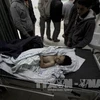 Thi thể một nạn nhân vụ oanh tạc của Israel xuống Dải Gaza ngày 24/12. AFP/ TTXVN
